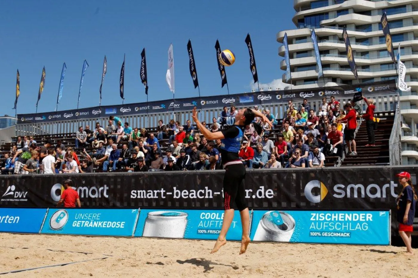 A beach volleyball in flight above the net