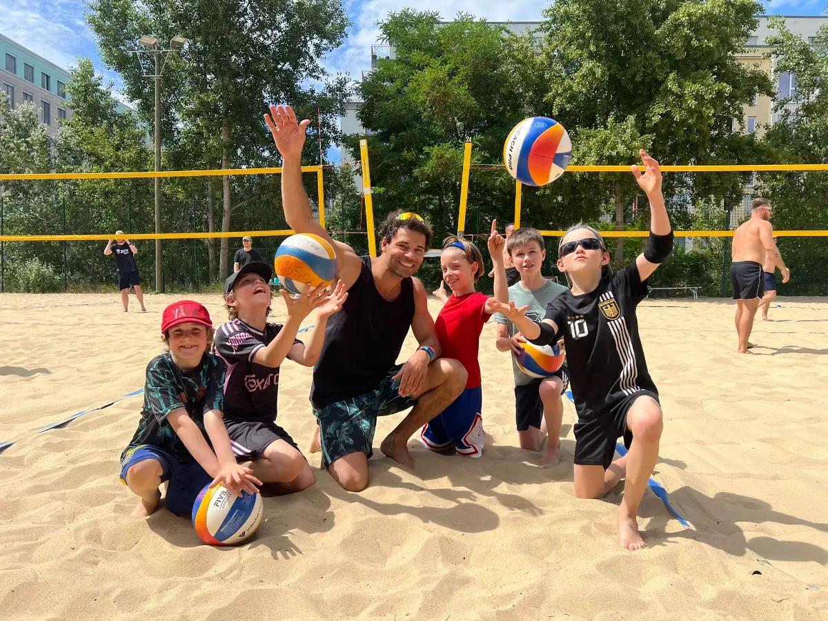 Kids at the beach volleyball camp with their coach
