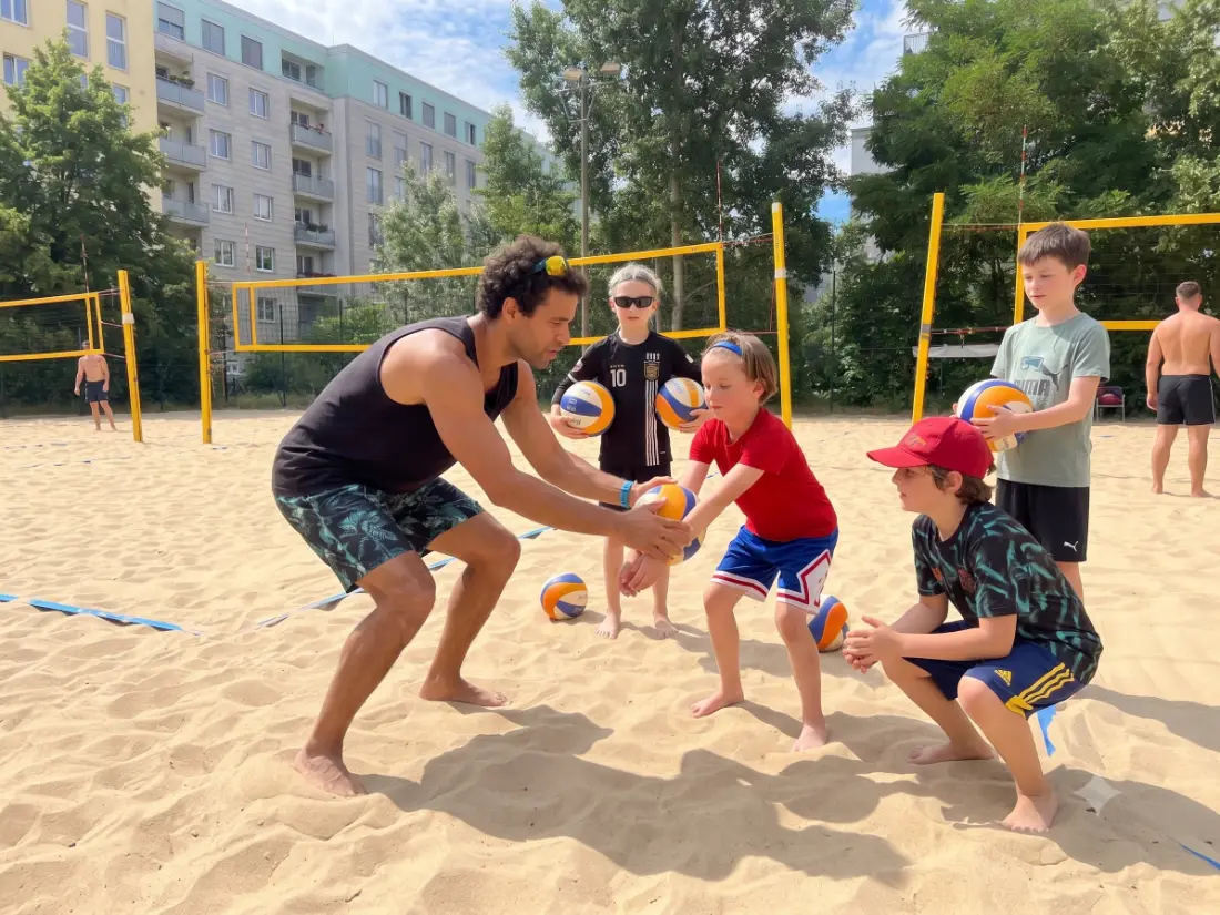 Trainer zeigt Kindern die Ballannahme beim Beachvolleyball in Berlin